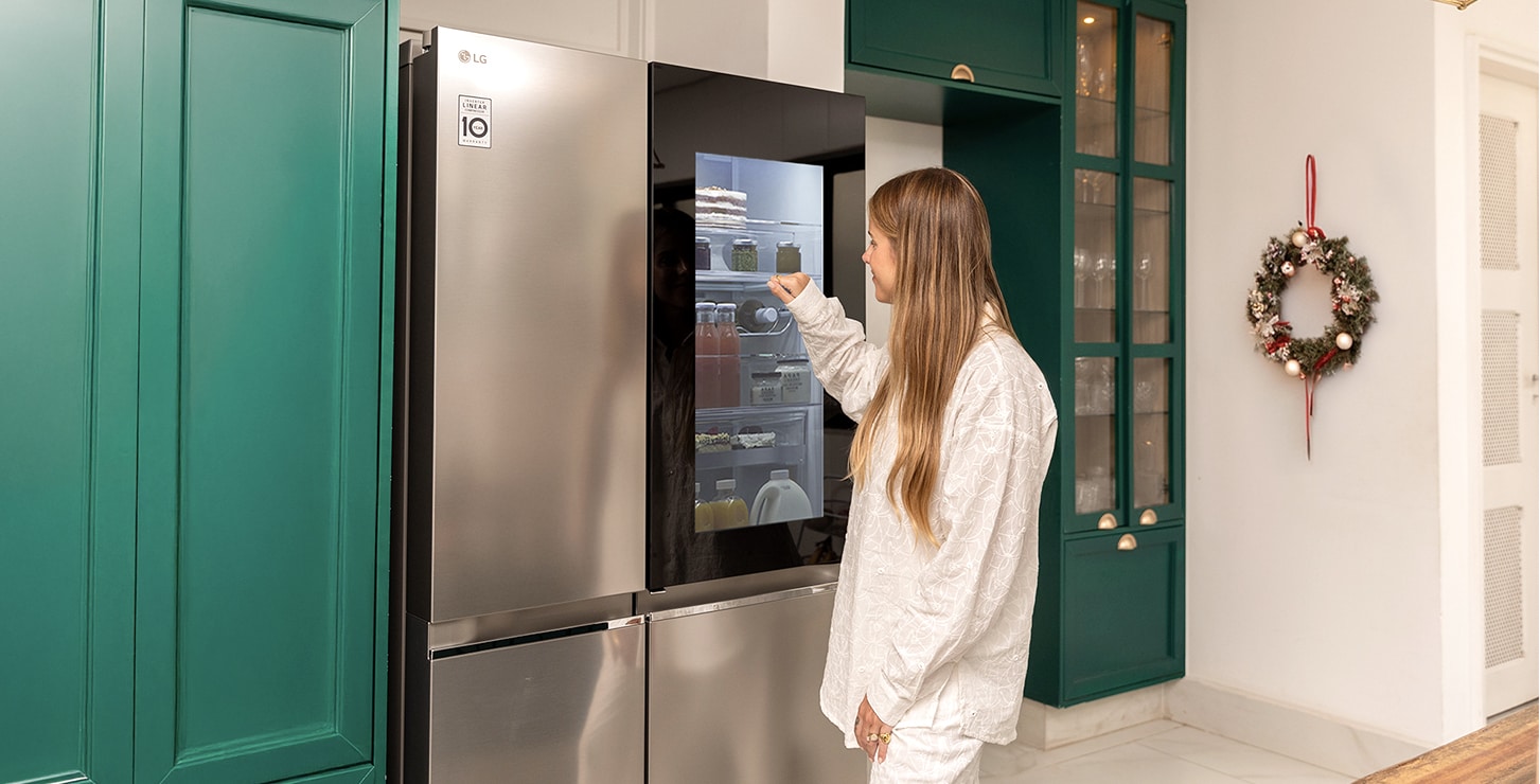 Una mujer está tocando la puerta del refrigerador LG InstaView.