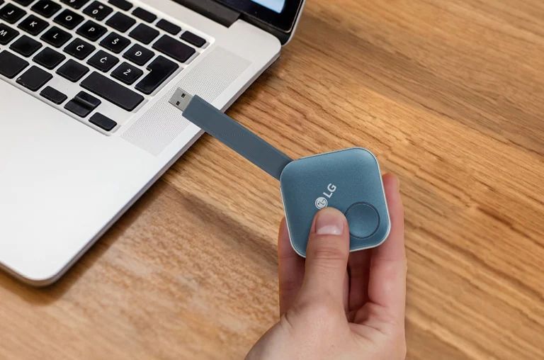After pairing, you can share a screen with LG Signage by simply plugging a USB dongle device into the personal PC. This image shows a person is holding the USB dongle and try to connect it to the PC.
