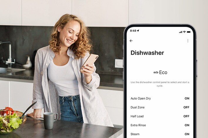 Una mujer configura las preferencias del ciclo de limpieza mediante la app LG ThinQ en la cocina.