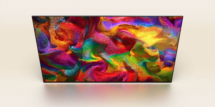 Las partículas de color estallan en la pantalla, luego los píxeles cambian lentamente a un primer plano de una pared pintada con un patrón colorido en la pantalla del televisor LG.