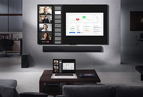 Obývací pokoj s výhledem z pohovky na televizor LG True Wireless a soundbar LG připevněné na stěně. Na konferenčním stolku leží notebook připojený k Zero Connect Boxu, který je pod stolem sotva vidět. Obrazovka notebooku s živým videohovorem se bezdrátově zrcadlí na televizní obrazovce. Není tu žádná změť kabelů a celý prostor díky tomu působí elegantně.