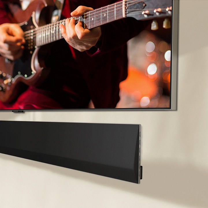 Natočený pohled na spodní část LG Soundbar a LG TV připevněné ke stěně.