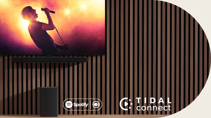 Televizor LG OLED C je umístěn na stěně a pod ním je pomocí exkluzivního držáku umístěn soundbar LG SC9S. Dole je umístěn subwoofer. Televizor zobrazuje scénu z koncertu.