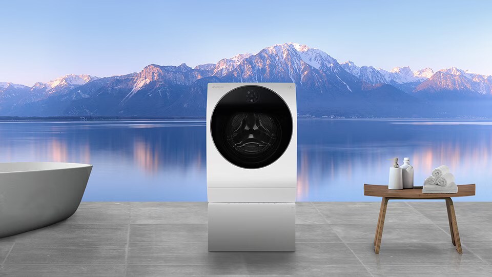LG SIGNATURE Pračka a vana jsou položeny v prádelně s výhledem na hory a řeku najednou za oknem.