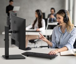 Žena se sluchátky na uších v call centru hovoří se zákazníkem.	