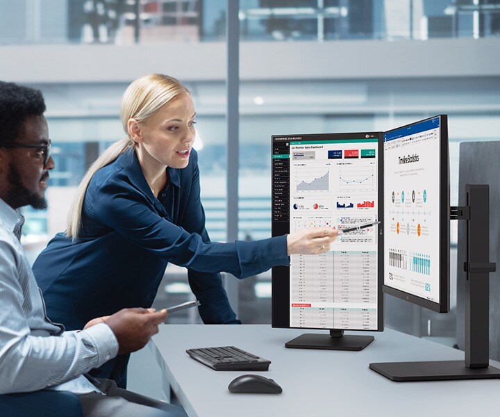 Dva zaměstnanci a zaměstnankyně diskutují a dívají se přitom na monitor v kanceláři.	