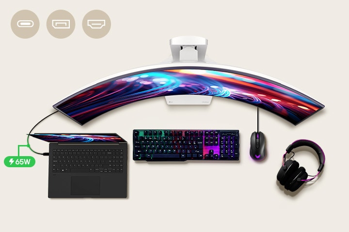 Uprostřed stolu je umístěn 45" herní monitor a kolem něj různá IT zařízení.	