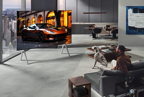Wohnzimmer mit einem LG True Wireless TV und einer LG Soundbar, die an der Wand befestigt ist. Die Zero Connect Box ist unter einem Beistelltisch neben der Couch kaum zu sehen – sie lässt sich praktisch überall aufstellen. Das gesamte Layout des Wohnzimmers wirkt ordentlich und aufgeräumt.