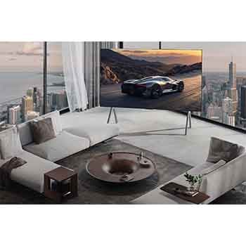 Geräumiges Wohnzimmer mit Blick auf eine Stadtlandschaft. Der LG OLED TV steht auf einem Standfuß. Das ultra-schlanke Design sorgt für eine beeindruckende Wirkung des Bildschirms. Die Zero Connect Box ist zu sehen, aber unauffällig aufgestellt. 