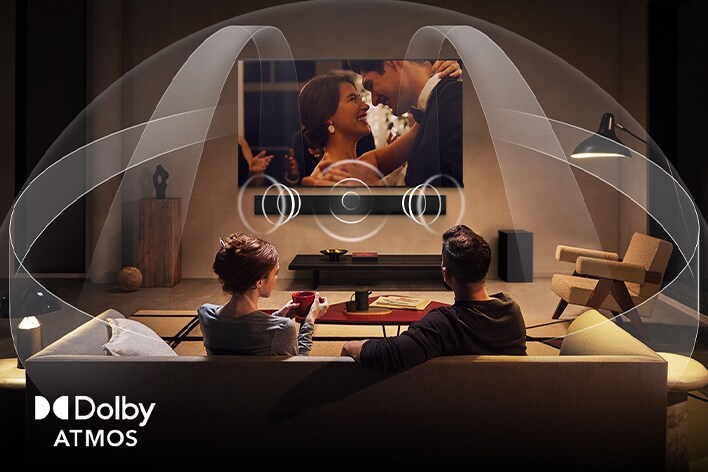 Paar schaut in einem spärlich beleuchteten und gemütlichen Wohnzimmer einen Film auf ihrem LG TV mit LG Soundbar. Grafiken zeigen, wie Dolby Atmos den ganzen Raum mit Klang aus allen Richtungen füllt. Das Dolby Atmos-Logo befindet sich in der unteren Ecke.