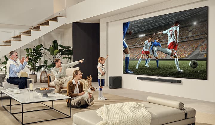 Eine Familie ist um ihren ultragroßen LG TV versammelt und sieht sich auf dem riesigen Bildschirm ein spannendes Fußballspiel an.
