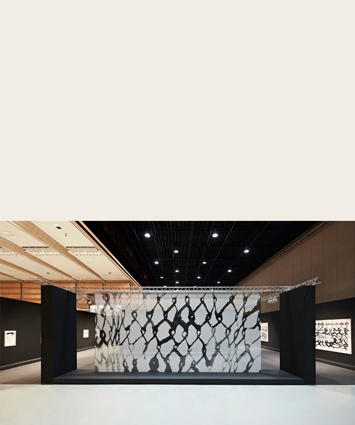 Kunst auf einem transparenten Panel in einer Ausstellungshalle.