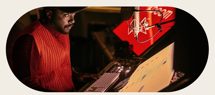 will.i.am está trabajando en el estudio mirando una pantalla colocada debajo de un micrófono.