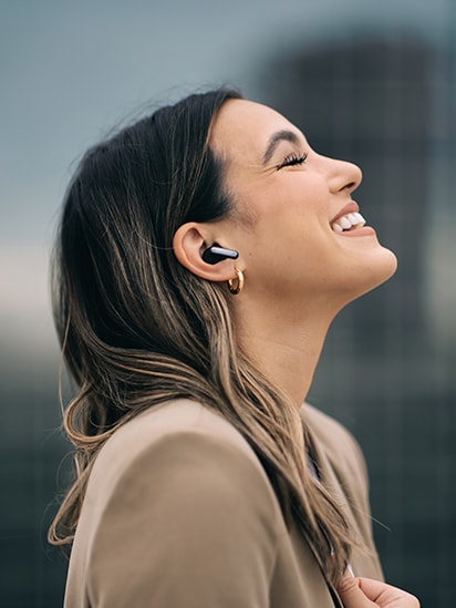 Woman wearing TONE Free black and enjoying music with closed eyes in the city