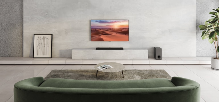 Zu sehen ist ein Fernseher, der ein Naturbild zeigt. Eine Soundbar, ein Subwoofer und 2 hintere Lautsprecher befinden sich in einem weiträumigen Wohnzimmer. Von der Soundbar geht eine Welle mit Gittermuster aus, die bildlich darstellt, wie das gesamte Wohnzimmer vermessen wird.