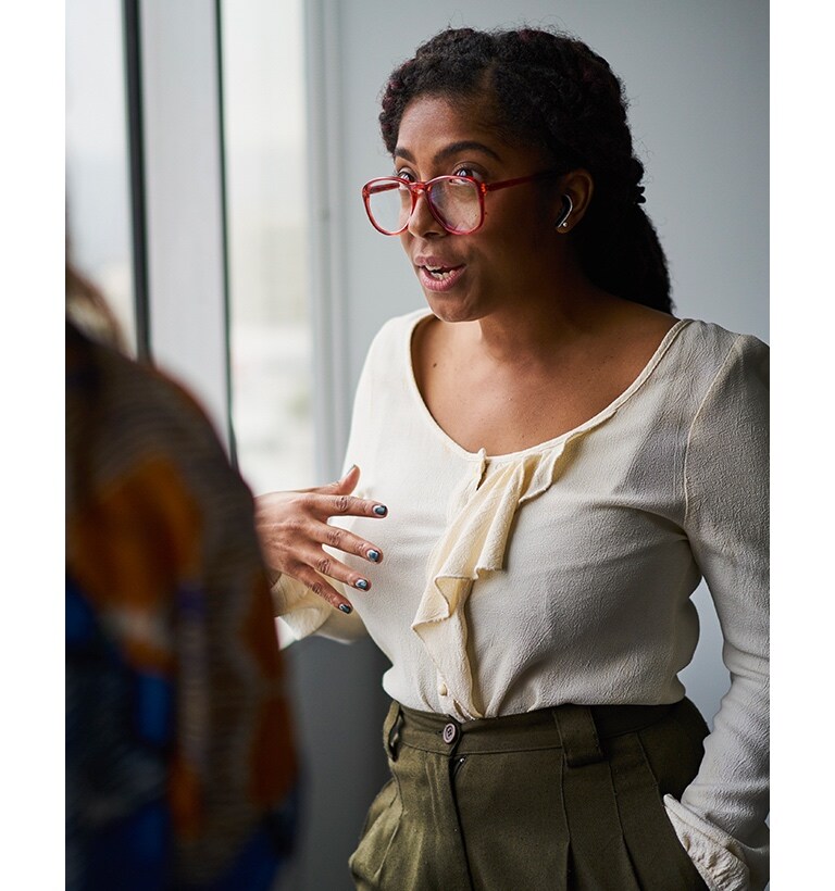 Zwei Frauen sprechen miteinander. Die Frau trägt Ohrhörer.