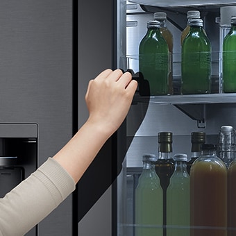 Die Vorderansicht eines InstaView®-Kühlschranks aus schwarzem Glas mit eingeschaltetem Licht innen. 