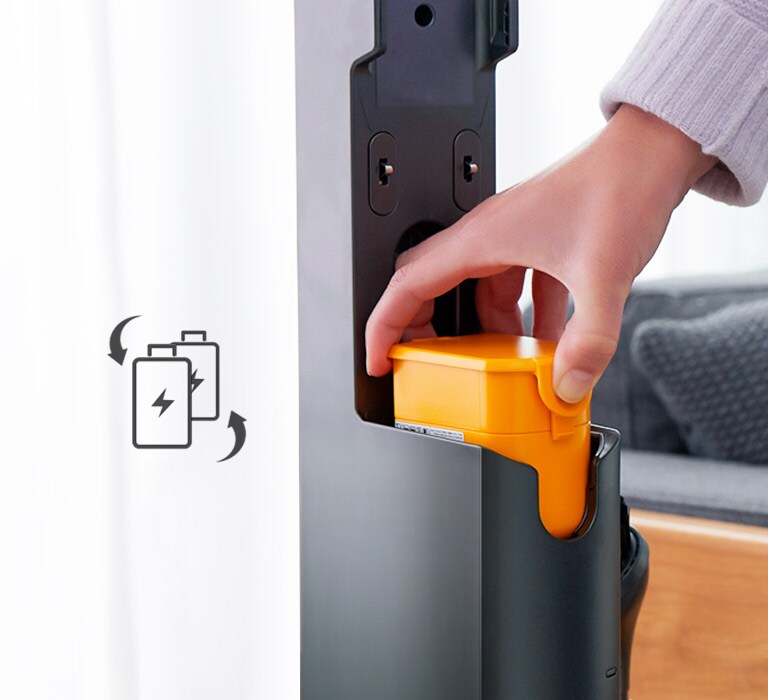 Eine Hand setzt den Akku in den Staubsauger ein. Auf der linken Seite befindet sich ein Symbol mit zwei Akkus mit  60 Minuten und Pfeilen an der Seite. Die Batterien bewegen sich, um anzuzeigen, dass sie ausgetauscht werden können.