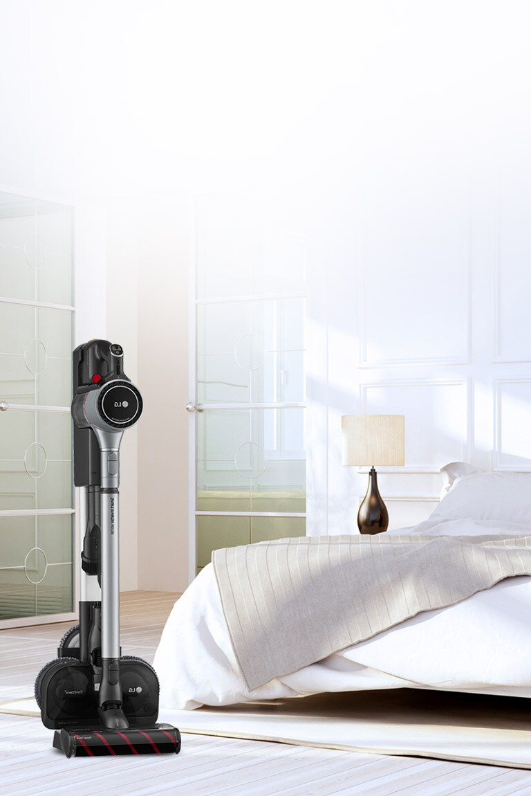 Der CordZero A9 Kompressor-Staubsauger steht in der Ladestation in einem Wohnzimmer in der Nähe des Sofas.
