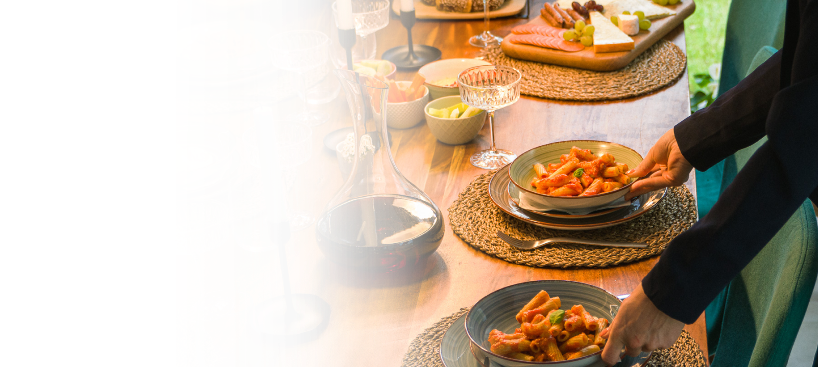 Eine Frau, die eine Hausparty vorbereitet, stellt Pasta auf einen mit Essen gefüllten Esstisch.