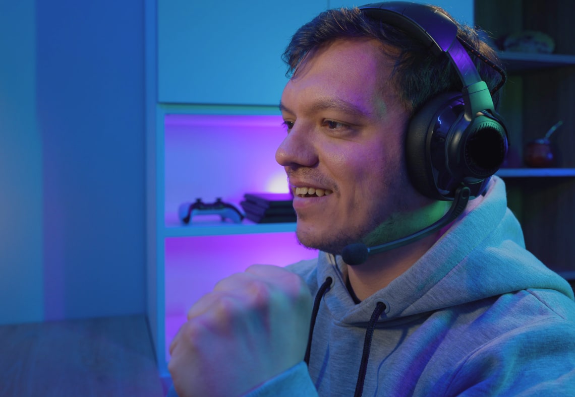 Ein Gamer trägt ein Headset und einen Hoodie und sieht während des Spielens aufgeregt aus.