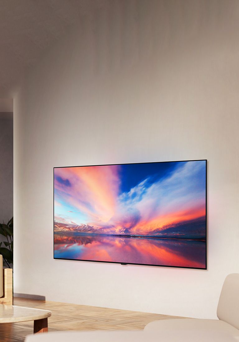 Der LG OLED TV B4 an der Wand eines neutralen Wohnraums, der ein buntes Foto eines Sonnenuntergangs über dem Meer zeigt. 	