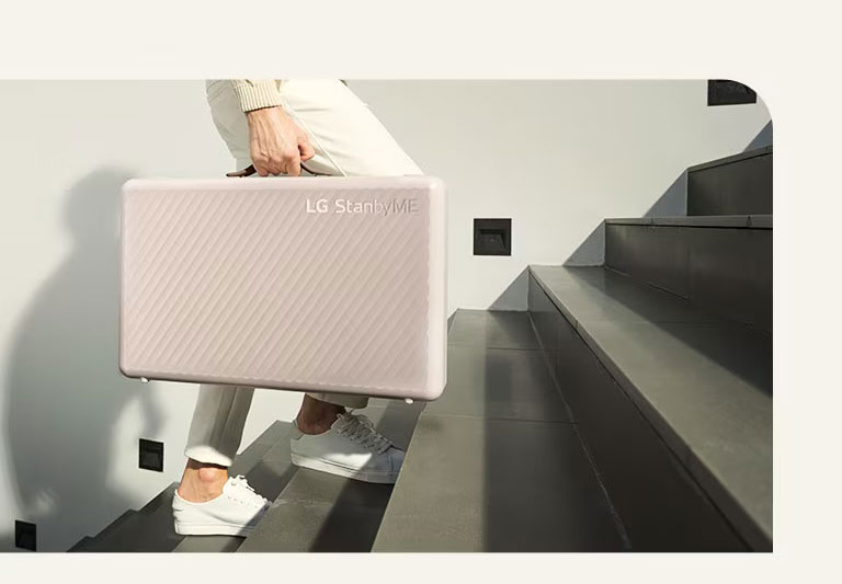 Ein Mann trägt den LG StanbyME Go mithilfe des Koffer-Designs.