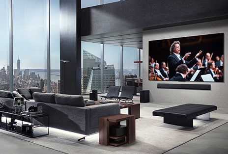 Living room with an LG True Wireless TV and LG Soundbar that's wall-mounted. The Zero Connect Box is barely seen under a side table by the couch, showing how it can easily be placed anywhere. The whole living room's layout is visually neat and tidy.