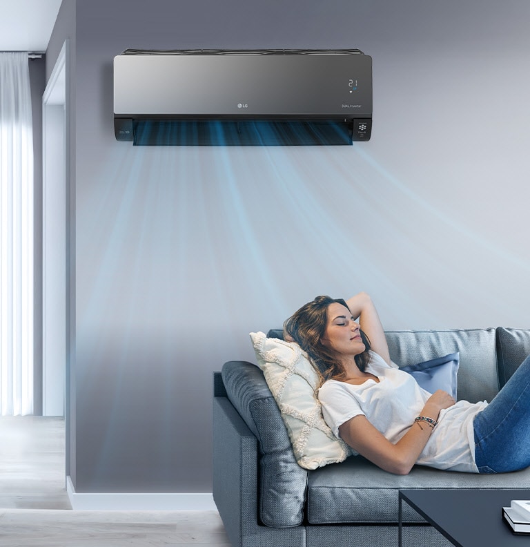 LG air conditioner cools a room with blue air streams as a woman relaxes on a gray sofa.
