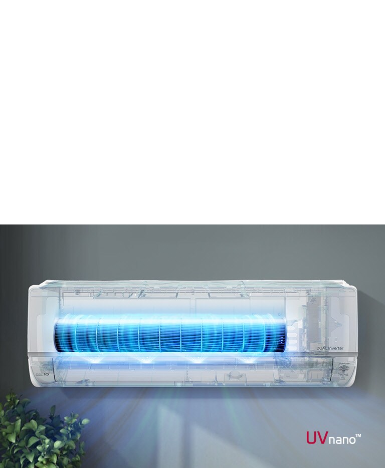 LG Dual Inverter air conditioner with UVnano technology, emitting blue light, mounted on a grey wall, above green plants.