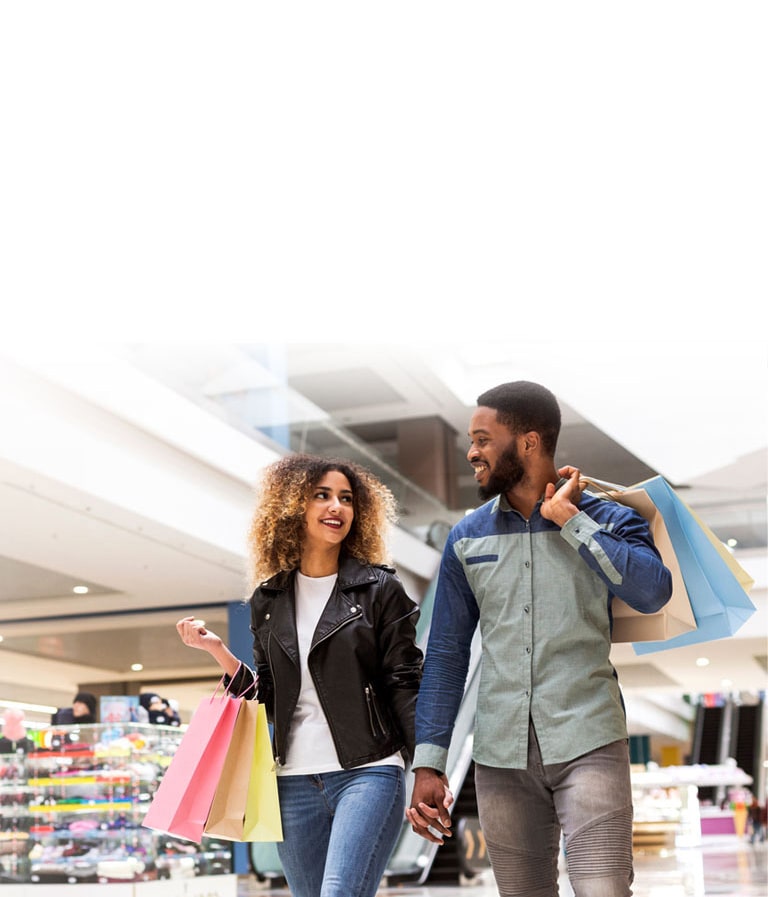 A couple shopping at a mall with colorful shopping bags.