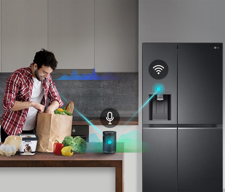 Persona desempaquetando alimentos en una cocina moderna con refrigerador LG negro y dispositivo inteligente.