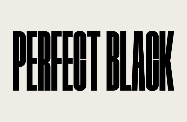 Las palabras “NEGRO PERFECTO” aparecen en mayúsculas resaltadas en negrita. Una escena muy nítida de unas montañas negras se eleva y tapa las letras y aparece un pueblo y unas dunas de arena. La copia negra desaparece detrás de un cielo negro.