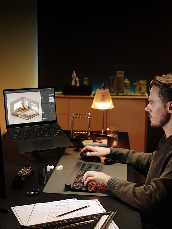 Imagen de un hombre sentado frente a un escritorio que hace un boceto en 3D con su portátil.	