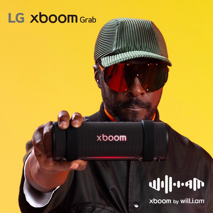 will.i.am con traje negro y gafas de sol sostiene xboom Grab junto a su cara.