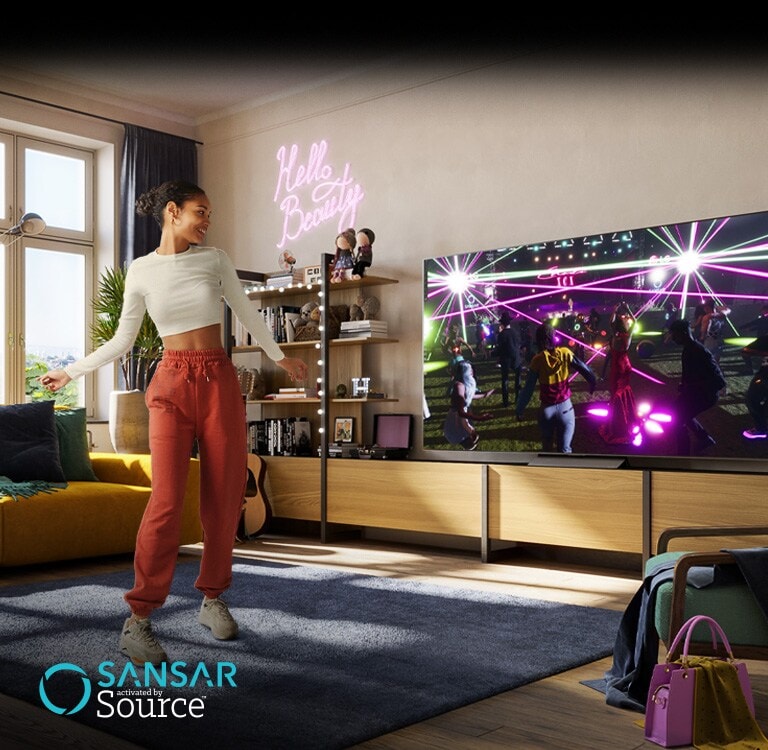 Una mujer está bailando en su habitación mientras ve un concierto en el metaverso de «Sansar» en el televisor.