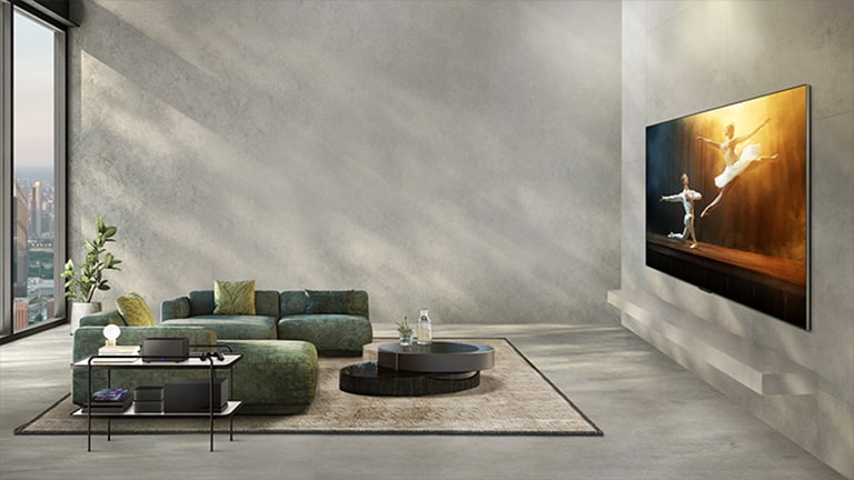 Une vidéo de LG OLED M3 sur le mur gris d'un espace de vie moderne joue un ballet à l'écran. Des câbles en pagaille, des systèmes audio et des consoles de jeux sont connectés à la télévision. Ensuite, tous les périphériques disparaissent et le boîtier Zero Connect Box apparaît sur une table latérale dans la pièce, offrant une vue dégagée sur l'écran.