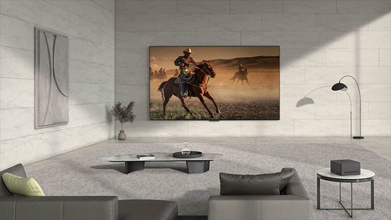 La vidéo s'ouvre sur le LG OLED M3 accroché au mur d'une pièce, avec des fils et des périphériques en pagaille connectés à la télévision. Une ligne bleue se déplace sur l'écran, les fils et les appareils disparaissent, puis la Zero Connect Box apparaît sur une table d'appoint. L'écran devient noir, ne laissant apparaître que la télévision et la boîte, en soulignant leur emplacement. La boîte et la télévision se déplacent vers deux autres endroits de la pièce et, à chaque fois, l'écran devient noir pour mettre en évidence leur emplacement. 