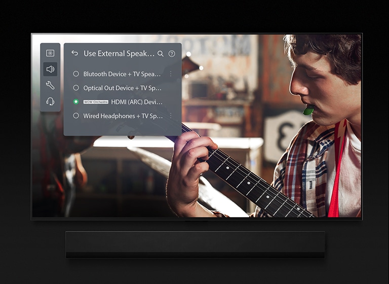 Image d'une LG OLED TV avec barre de son. Une vidéo d'un garçon jouant de la guitare s'affiche à l'écran avec les paramètres du mode Soundbar en surimpression. 