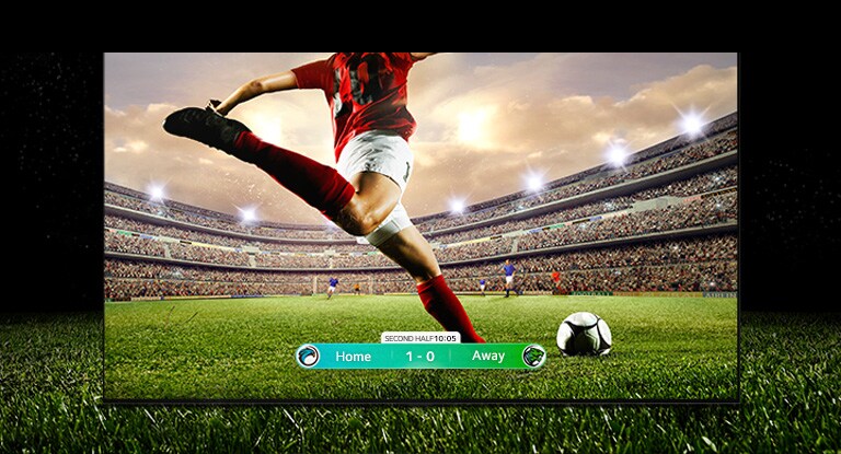 Image de l’écran diffusant un match de football avec un joueur portant un maillot rayé rouge qui s’apprête à tirer dans le ballon. Le score du jeu est visible en bas de l’écran. La pelouse verte du terrain s’étend au-delà de l’écran jusqu’à la toile de fond noire.