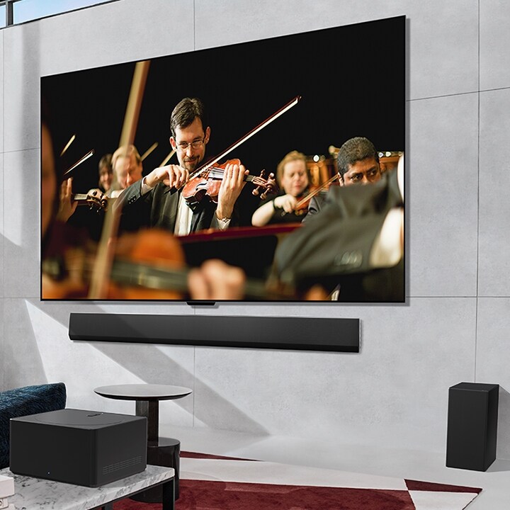 Un TV LG OLED, diffusant un orchestre à l’écran, fixée à plat sur un mur et un boîtier Zero Connect** placé en face.