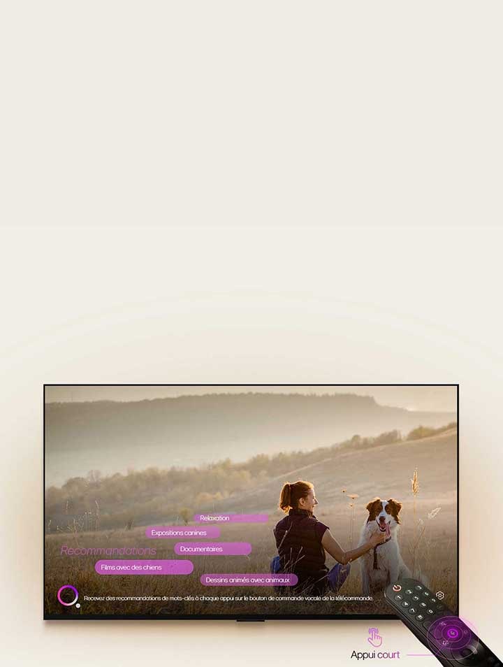 Une LG TV montre l’image d’une femme et d’un chien dans un champ. En bas de l’écran, le texte : « Recommande de nouveaux mots clés chaque fois que vous appuyez sur le bouton de micro sur la Télécommande » est affiché à côté du graphique de cercle rose-violet. Les barres roses affichent les mots clés suivants : Films avec des chiens, concours canin, documentaire, relaxation, animations avec animaux. Face à la LG TV, la Télécommande Magic LG est pointée vers le téléviseur avec des cercles concentriques violet fluo autour du bouton du micro. À côté de la télécommande, un graphique d’un doigt appuyant sur un bouton et le texte « Appuyer brièvement » est affiché.