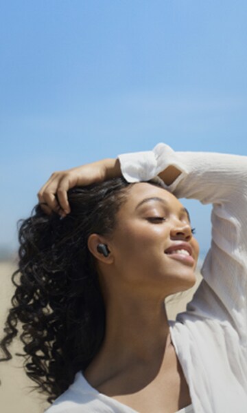 Une femme écoute de la musique avec les écouteurs LG Tone Free