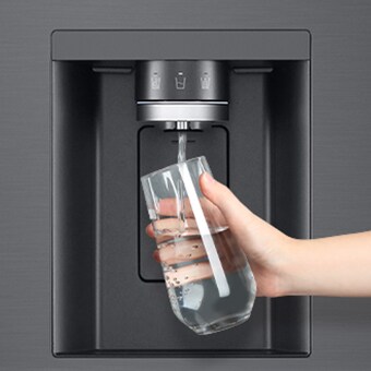 Une personne prend de l’eau du distributeur du réfrigérateur dans un verre