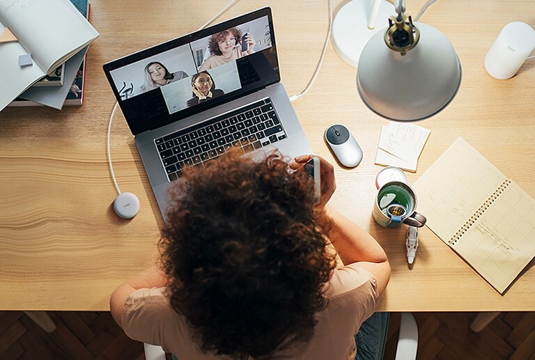 Une femme travaille sur un ordinateur et utilise la connexion sans fil pour participer à une conférence téléphonique.