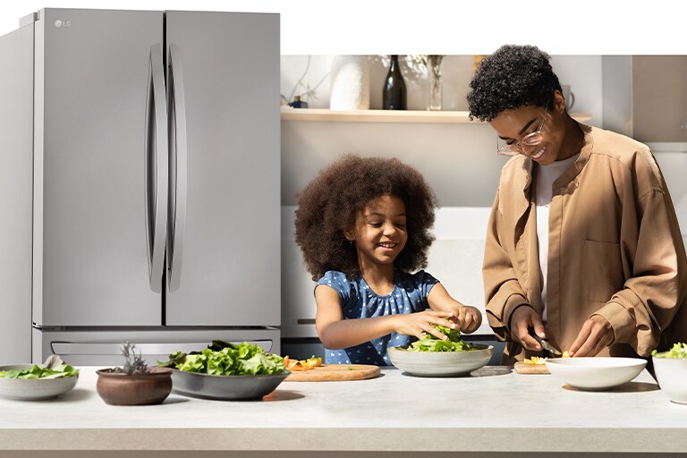 Un adulte et un enfant préparent à manger dans la cuisine, avec un réfrigérateur éclairé