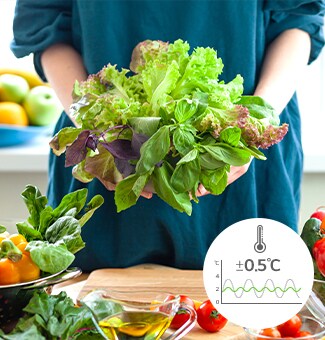 Une personne tient des légumes dans les mains et la température en bas à droite ±0.5°C indique la fraîcheur pour une longue durée