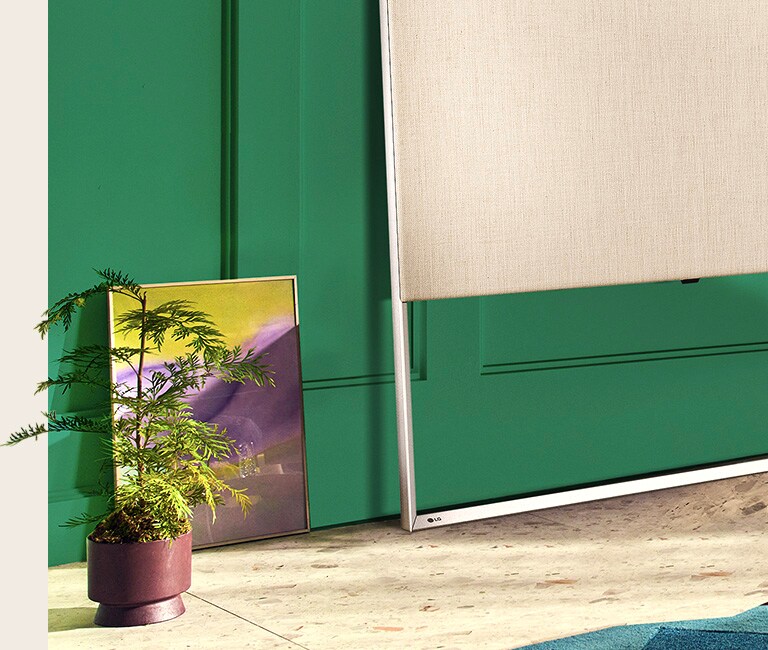 Gros plan sur le EASEL au sol appuyé contre le mur avec une peinture et une plante décorative.