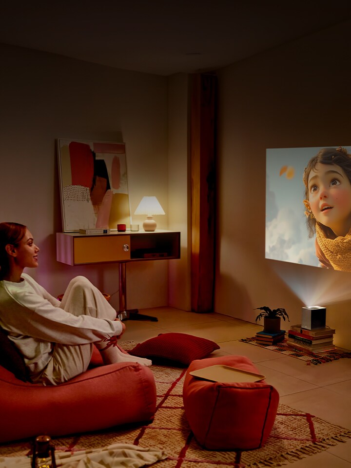 Une femme regardant un film avec le LG CineBeam.