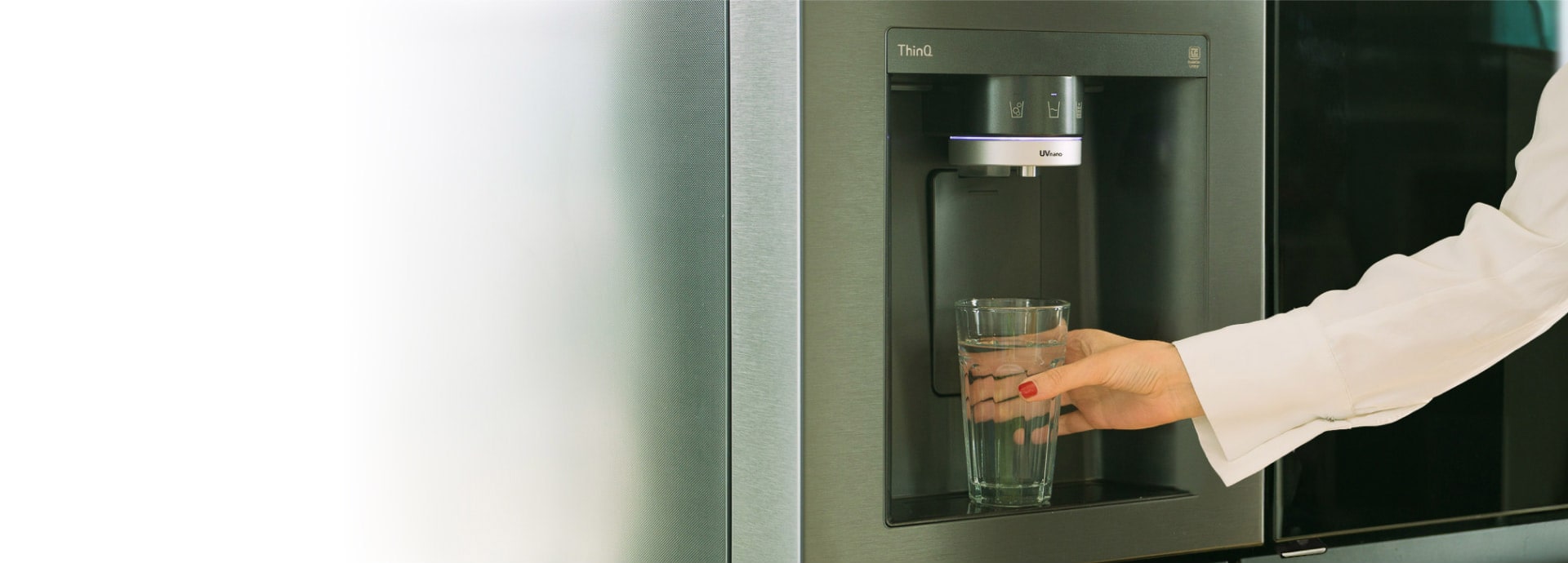 Une femme se sert une tasse d'eau dans le distributeur d'eau du réfrigérateur LG InstaView American.